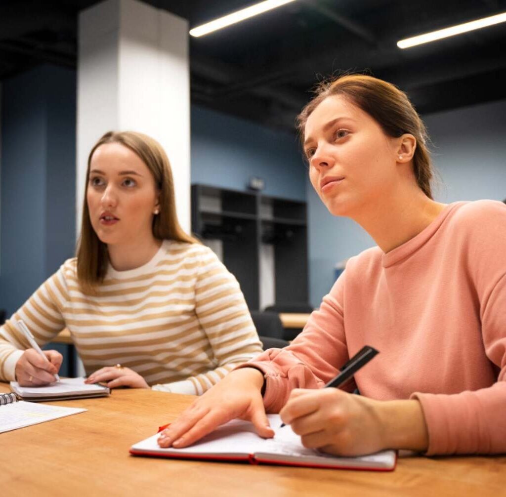 : Student taking a language proficiency test in a classroom with exam papers and a laptop